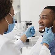 young man sitting in dental chair and smiling at his dentist